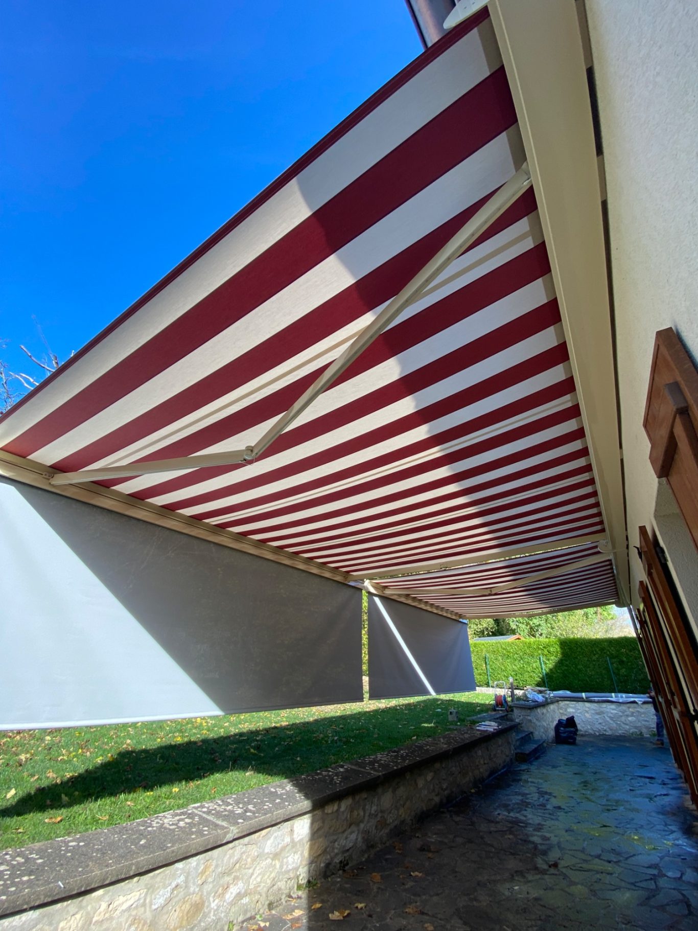 Auvent rayé rouge et blanc, vu de dessous, avec un ciel bleu en arrière-plan.
