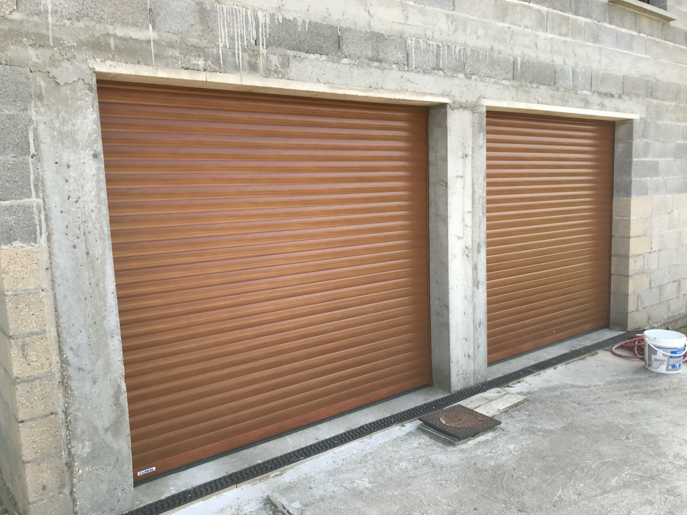 Deux rideaux métalliques bruns sur un mur en béton.