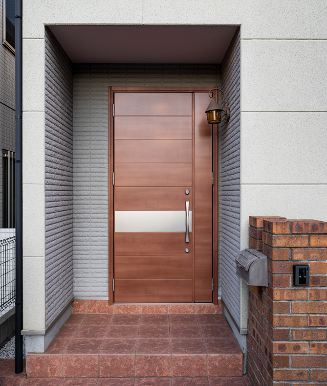 Porte d'entrée en bois avec un panneau métallique, murs en briques.