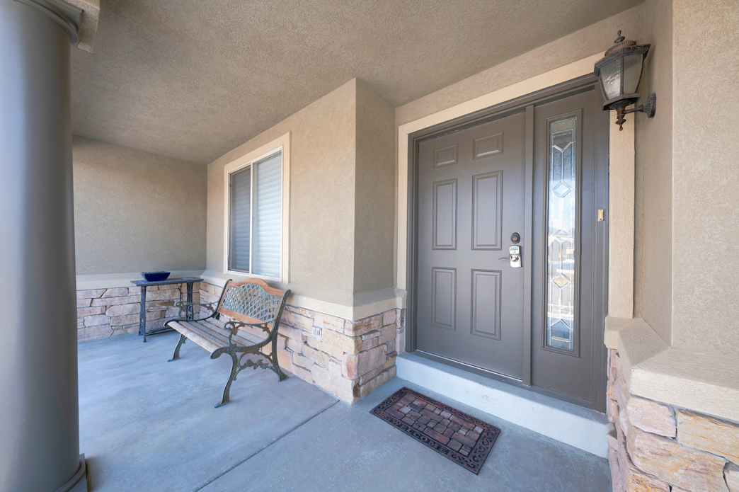 Entrée d'une maison avec une porte marron et un banc en bois à côté.