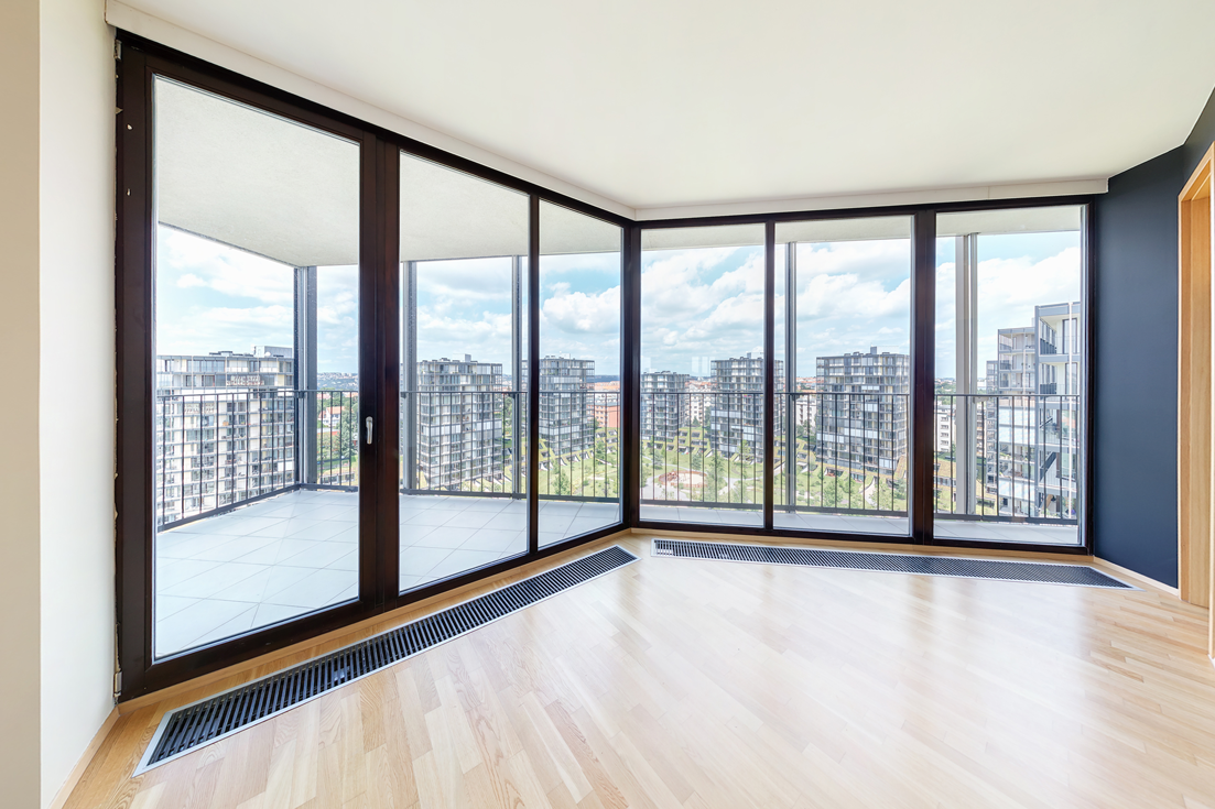 Intérieur d'un appartement moderne avec de grandes fenêtres et vue sur la ville.